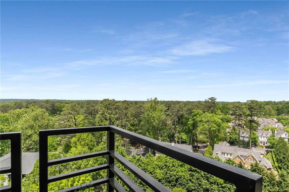 Panoramic view from a balcony overlooking trees and houses.