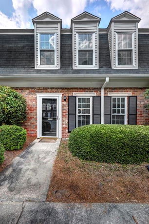 Front view of a two-story brick house with dormer windows.