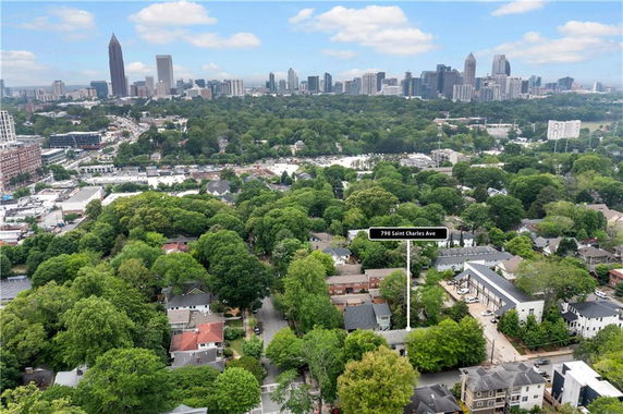 Aerial view of a suburban area with numerous houses and a city skyline in the background.