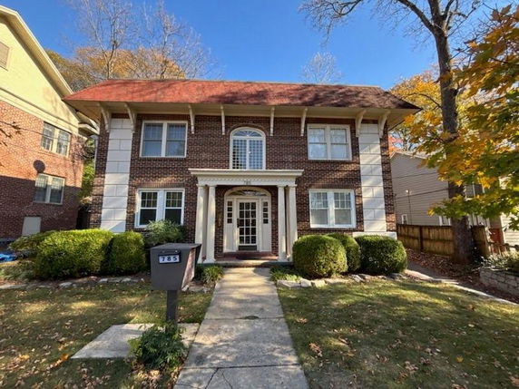 Front view of a two-story brick house with a red roof and white columns.