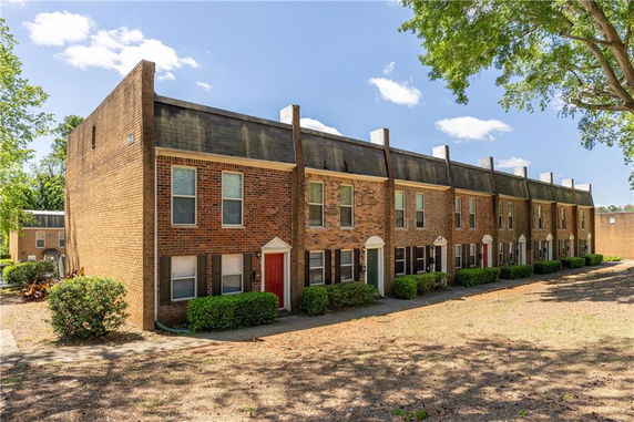 Front view of a row of brick townhouses with pitched roofs.