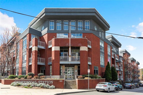 Front view of a modern multi-story brick building with large windows and balconies.