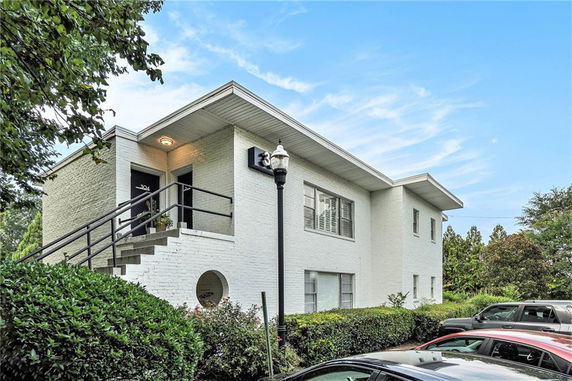 Front view of a two-story white brick house with outdoor stairs and railings.