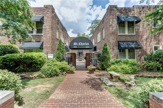 Front view of a brick apartment building with awnings and gated entrance.