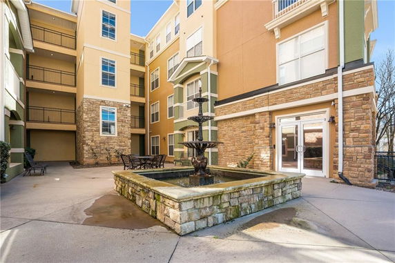 Front view of a multi-story building with stone accents and a central courtyard featuring a fountain.