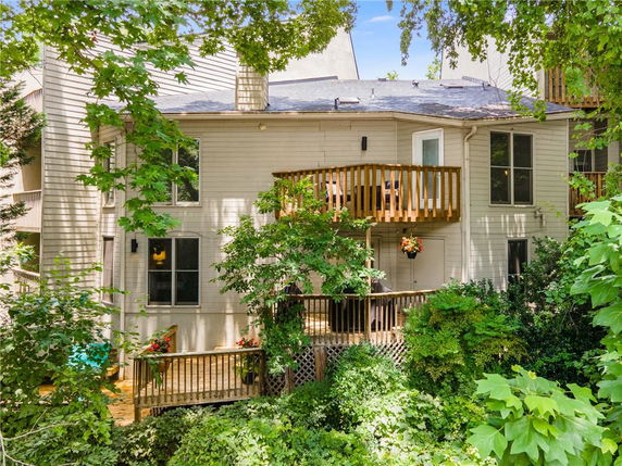 Back view of a multi-story house with a wooden balcony and deck.