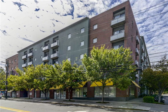 Front view of a multi-story building with balconies and a brick facade.