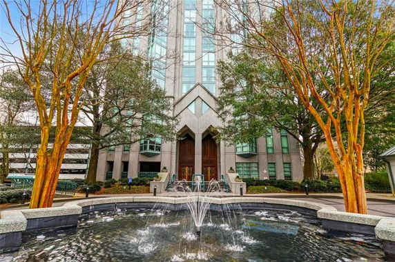 Front view of a multi-story building with a fountain in the foreground.