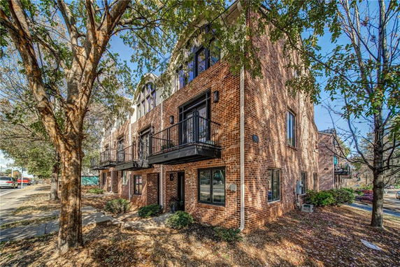 Front view of a multi-story brick residential building with balconies.