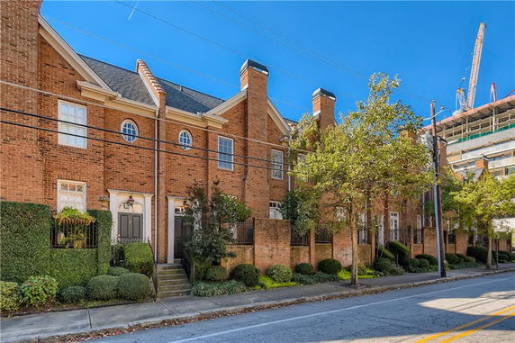 Front view of a row of brick townhouses with gabled roofs and round windows.