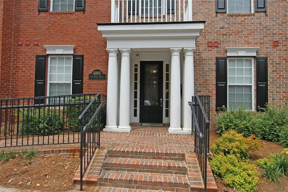 Front view of a brick house with white columns and black shutters.