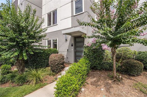 Front view of a modern multi-story house with landscaped entrance.