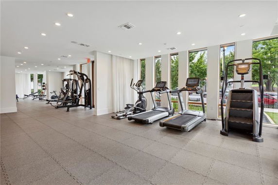 Interior view of a gym with exercise equipment and large windows.