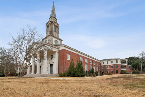 Front view of a large brick building with a tall spire and columns at the entrance.