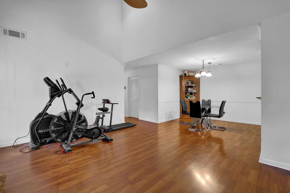 Room with exercise equipment and dining table on wooden flooring