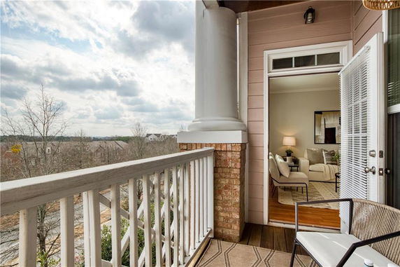 View from a balcony with a glimpse of surrounding residential area and living room interior.