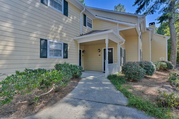 Front view of a two-story house with light yellow siding and a covered entrance.