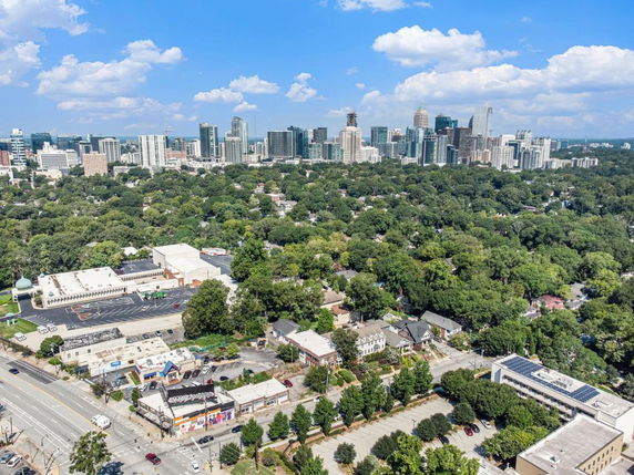 Aerial view of a cityscape with tall buildings and surrounding greenery on a clear day.
