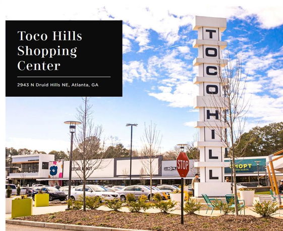 Front view of a shopping center with a tall sign displaying the name.