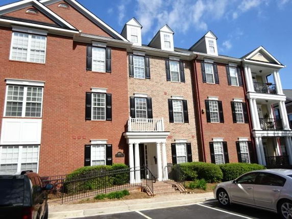 Front view of a three-story brick building with multiple windows and a small entrance balcony.