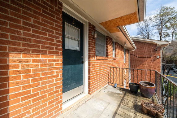 Front view of a brick building with a black door labeled '2' and railing.
