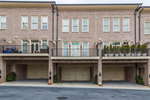 Front view of a multi-story brick townhouse with balconies and garages.