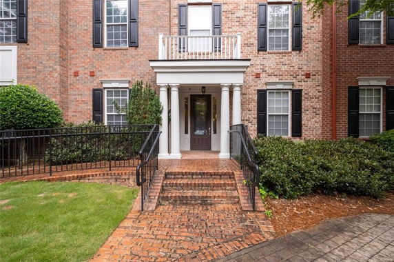 Front view of a multi-story brick building with black shutters and a columned entrance.