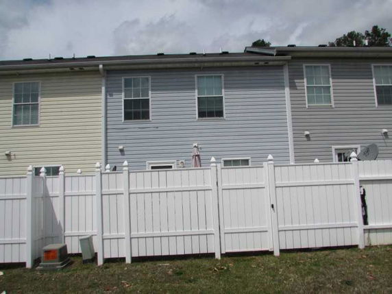 Back view of a two-story building with a white fenced yard.