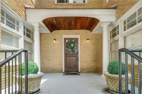 Front entrance of a brick house with a decorative door and white columns.