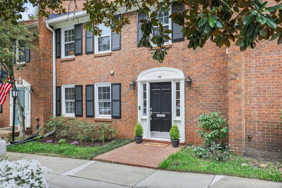 Front view of a two-story brick townhouse with black shutters and a black front door.