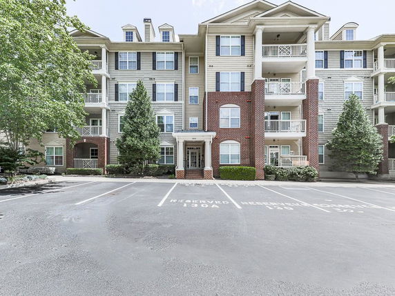 Front view of a multi-story apartment building with balconies and brick accents.