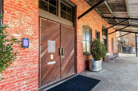 Front view of a brick building with wooden double doors and a covered walkway.