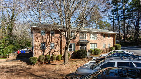 Front view of a two-story brick building with parked cars in front.