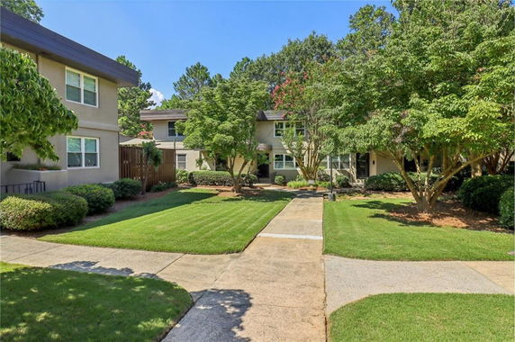 Front view of a residential two-story building with a pathway and surrounding greenery.