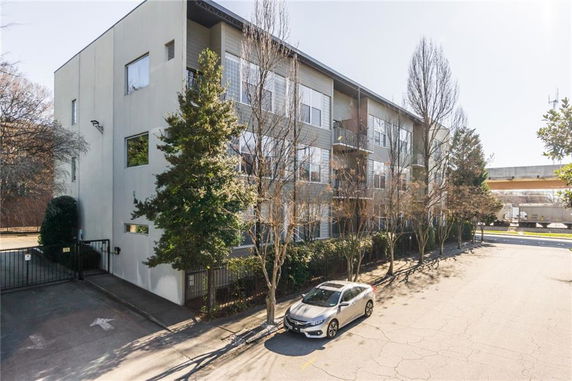 Front view of a multi-story apartment building with gated parking area.