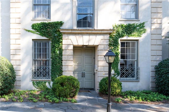 Front view of a house with green vines and a central entrance door.