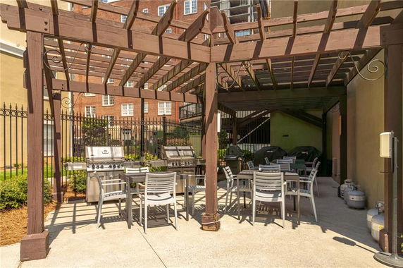 Outdoor area with barbecue grills and seating under a pergola.