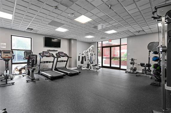 Indoor gym with treadmills, exercise bikes, and weight training equipment.