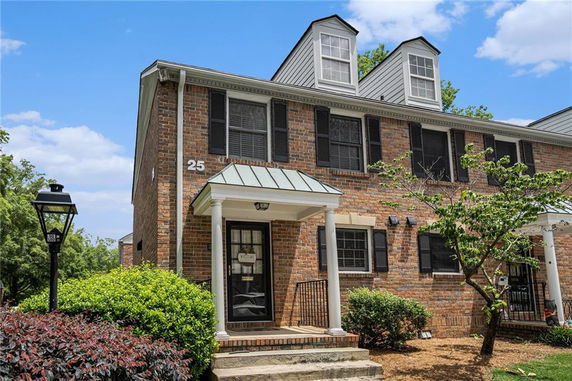 Front view of a two-story brick townhouse with dormer windows and a small front porch.