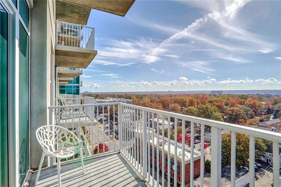 Balcony view overlooking a cityscape and tree-lined area with a clear sky.