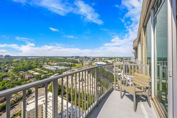 Balcony view overlooking a cityscape and greenery.