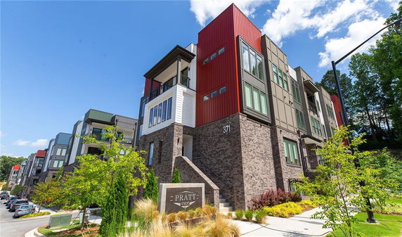 Front view of a modern multi-story apartment building with a brick facade and colorful panels.