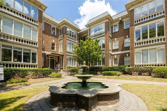 Front view of a multi-story residential building with large windows and a central courtyard fountain.