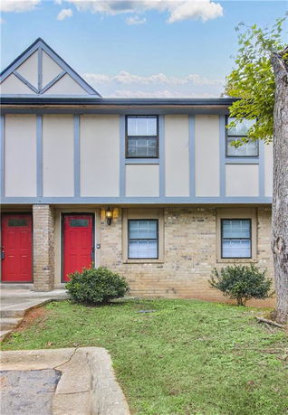 Front view of a two-story townhouse with red doors and brick facade.