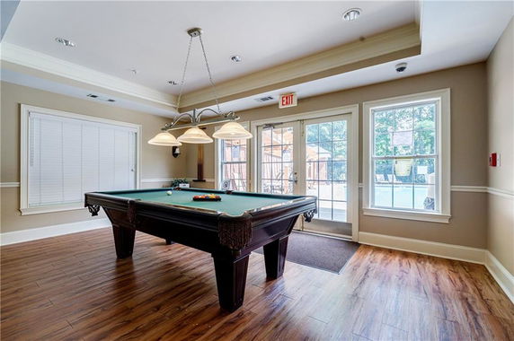 Indoor clubhouse room with a billiards table and large windows.