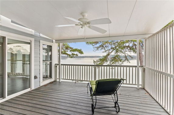 Covered porch area with a chair overlooking a scenic view of water and trees.