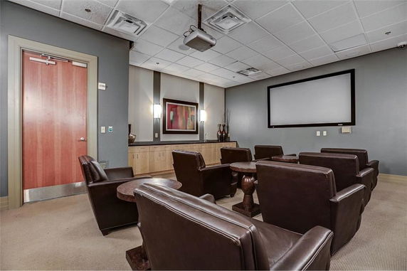 Indoor room with a screen and several leather chairs arranged like a small theater.