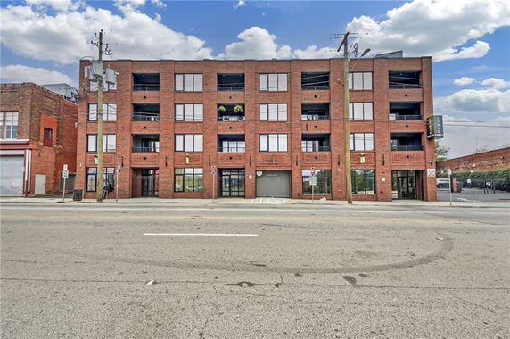 Front view of a four-story brick building with large windows and balconies.