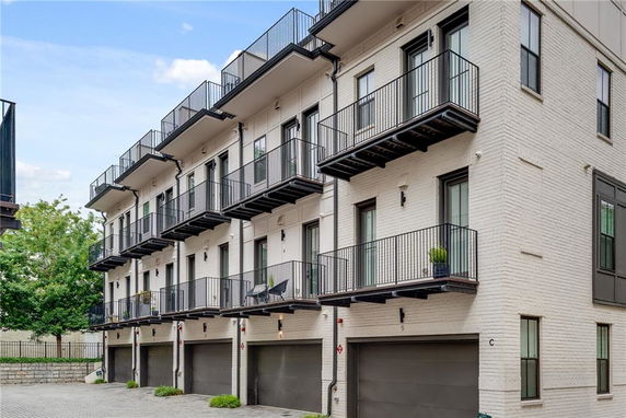 Front view of a multi-story building with balconies and garage doors.