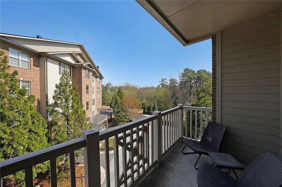 View from a balcony overlooking a residential building and surrounding trees.
